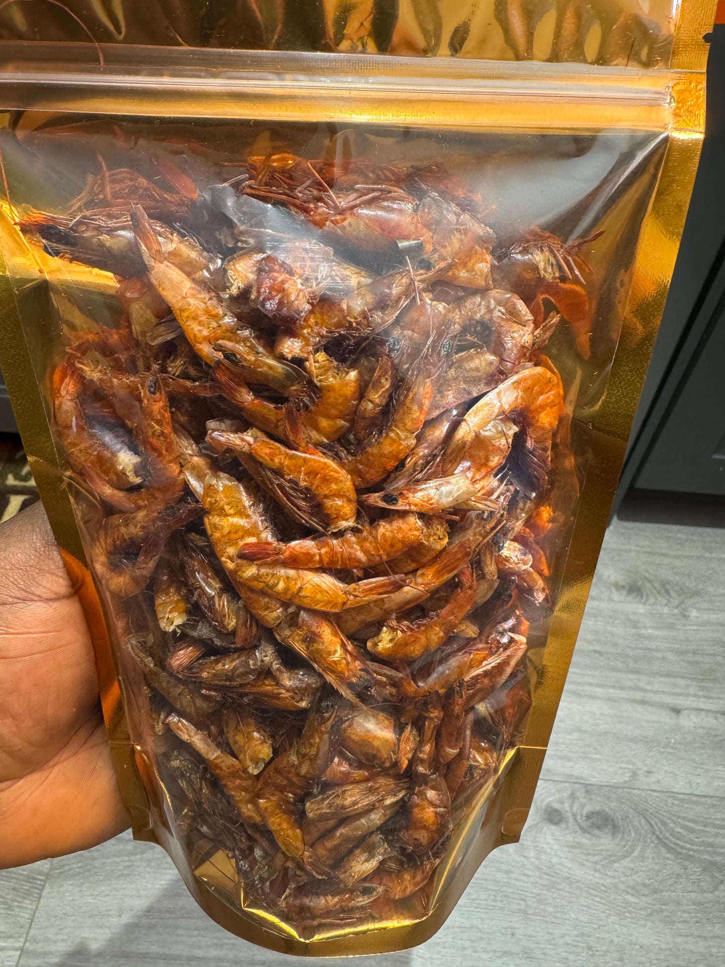 A clear plastic package filled with smoked prawns, held by a person with the top of the package visible.